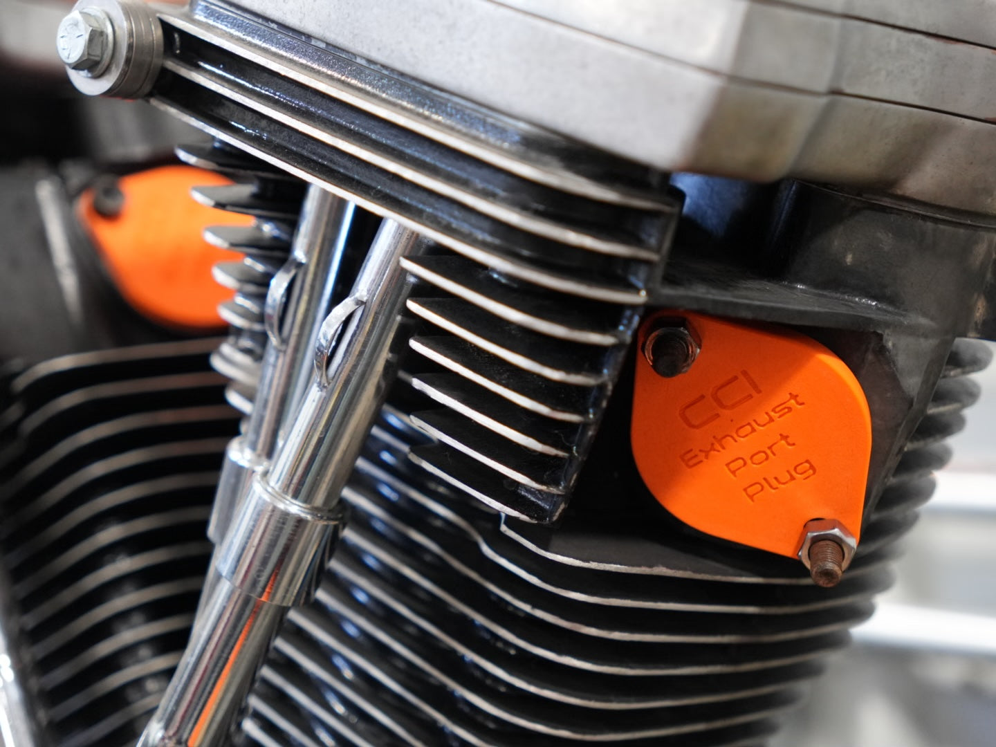 Close-up of a motorcycle engine with an orange CCI exhaust port plug.